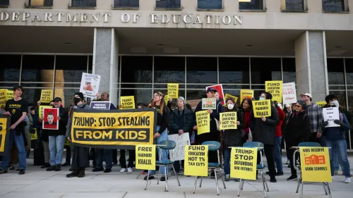 محتجون أمام وزارة التعليم يحملون لافتات تطالب بتمويل التعليم وعدم تقليص الميزانية، في سياق استعداد ترامب لتفكيك الوزارة.