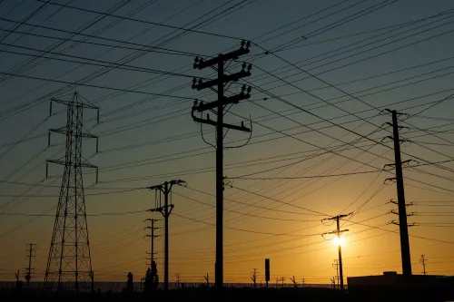 أبراج كهرباء silhouetted against a sunset, تمثل زيادة الطلب على الطاقة وتأثيره على أسعار الكهرباء في الولايات المتحدة.