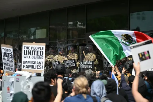 تظاهرة حاشدة أمام قوات الحرس الوطني في كاليفورنيا، مع لافتات تدعو للدفاع عن العائلات المهاجرة، تعكس التوترات السياسية الحالية.