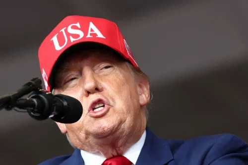 دونالد ترامب يرتدي قبعة حمراء مكتوب عليها USA يتحدث أمام ميكروفون خلال تجمع سياسي، مرتبط بقرار تعليق عقوبات الوقود الروسي.
