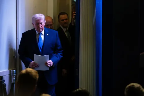 ترامب يدخل قاعة المؤتمر حاملاً ورقة، مع إضاءة خافتة خلفه، في سياق حديثه عن الرسوم الجمركية وتأثيرها على الاقتصاد الأمريكي.