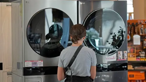 امرأة تتفقد غسالة ملابس وثلاجة في متجر للأجهزة، مع التركيز على تأثير التعريفات الجمركية على الأسعار.