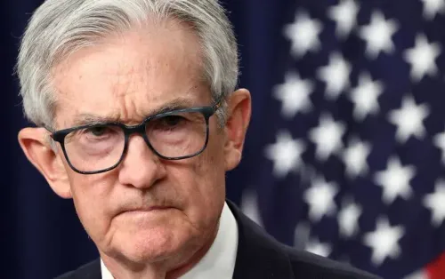 وجه رئيس الاحتياطي الفيدرالي جيروم باول، مع تعبير جاد، أمام العلم الأمريكي، مما يعكس التوترات الاقتصادية والسياسية الحالية.