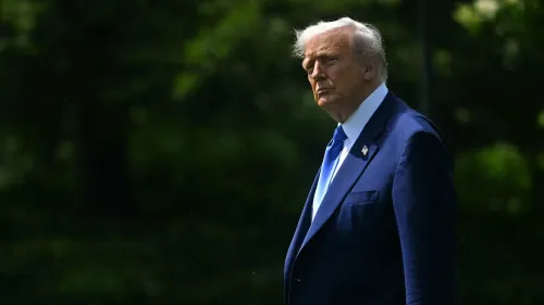 دونالد ترامب يقف في حديقة، مرتديًا بدلة زرقاء وربطة عنق زرقاء، مع خلفية طبيعية. تعكس تعابيره التوتر في ظل الحرب التجارية مع الصين.