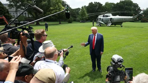 ترامب يتحدث للصحفيين في حديقة البيت الأبيض، محاطًا بكاميرات ومراسلين، مع هليكوبتر خلفه، في سياق مناقشات حول الاحتجاجات.