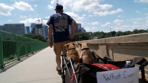 رجل يمشي على جسر مع كلبين من فصيلة الشيواوا في عربة، مرتديًا قميصًا يحمل علم أمريكا، في إطار مظهر حضري.