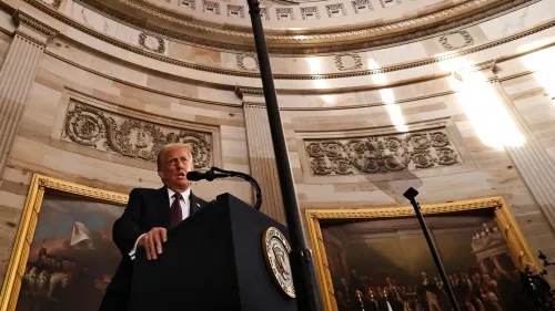 دونالد ترامب يتحدث في حفل تنصيبه الرئاسي، محاط بديكورات تاريخية وإضاءة خافتة، مما يعكس أهمية المناسبة وتأثيرها السياسي.