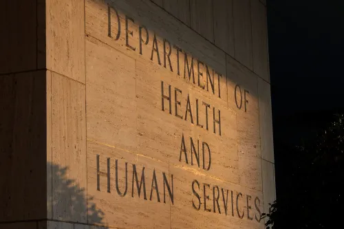 واجهة مبنى وزارة الصحة والخدمات الإنسانية، مع إضاءة خافتة، تعكس الجهود الفيدرالية للتحقق من أهلية برنامج Medicaid.