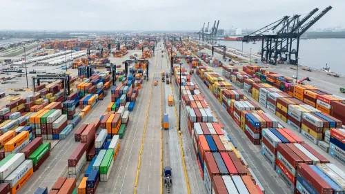 صورة لميناء مزدحم يحتوي على حاويات شحن ملونة، تعكس نشاط التجارة الدولية وتأثير الرسوم الجمركية المقترحة.