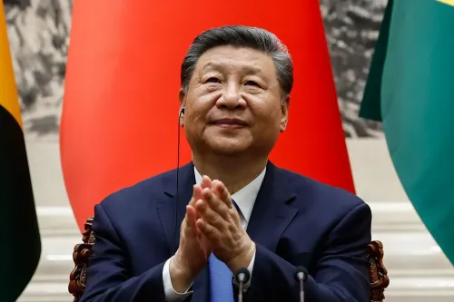 شي جين بينغ، الرئيس الصيني، مبتسمًا أثناء مؤتمر، مع العلم الصيني خلفه، في سياق التوترات التجارية مع الولايات المتحدة.