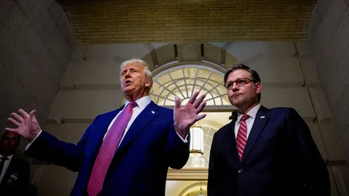 ترامب يتحدث بحماس مع مايك جونسون في الكابيتول، مع خلفية معمارية تعكس أجواء الضغط السياسي قبل التصويت على مشروع قانون مهم.