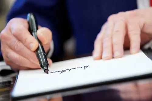 تظهر يد تكتب توقيع الرئيس دونالد ترامب على ورقة، في إطار جهود وزارة الخزانة لإصدار عملات تحمل توقيعه.