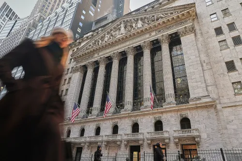 واجهة بورصة نيويورك مع أشخاص يسيرون في الشارع، تعكس النشاط الاقتصادي والتقلبات في سوق الأسهم خلال فترة ولاية ترامب.