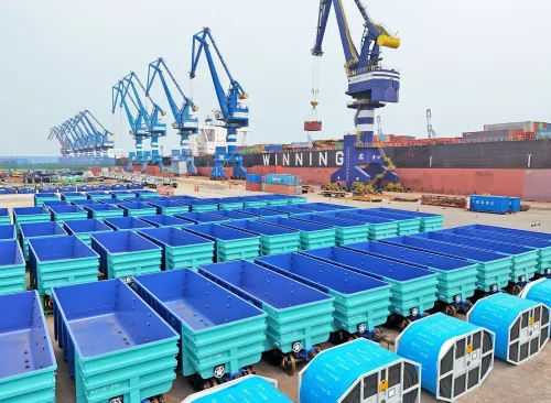 مستودع شحن يحتوي على حاويات زرقاء وشاحنات، مع رافعات في الخلفية، يعكس تأثير التعريفات الجمركية على التجارة الأفريقية.