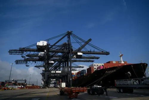 صورة لميناء أمريكي يظهر فيها رافعات تحميل كبيرة وسفينة شحن محملة بالحاويات، تعكس التحديات الحالية في الواردات والتعريفات الجمركية.