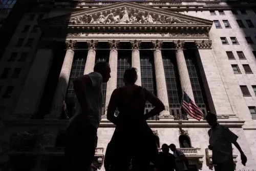 واجهة بورصة نيويورك مع أشخاص يتحدثون في المقدمة، تعكس حالة عدم اليقين في الأسواق المالية بعد تمرير قانون الضرائب.