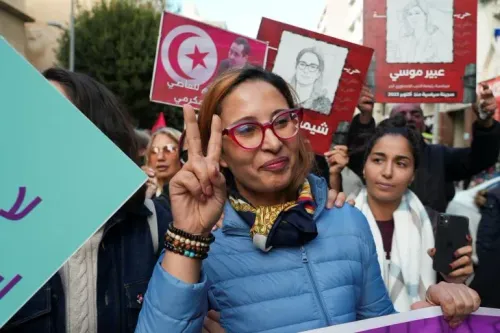 شيماء عيسى، ناشطة معارضة، ترفع علامة النصر خلال مظاهرة في تونس، وسط لافتات تدعو للحرية ورفض الاستبداد.