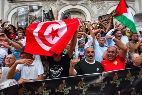 محتجون تونسيون يرفعون العلم الوطني وسط تظاهرات ضد الأوضاع الاقتصادية والسياسية المتدهورة في تونس.
