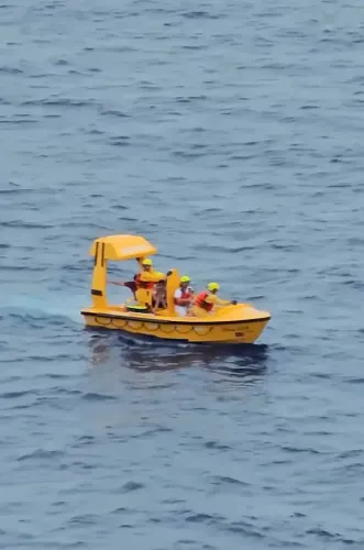 قارب إنقاذ أصفر يحمل طاقمًا من المنقذين في المياه، حيث تم إنقاذ أب وابنته الصغيرة بعد سقوطهما من سفينة ديزني دريم.