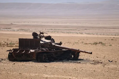 دبابة مدمرة في منطقة صحراوية بسوريا، تعكس آثار الصراع المستمر، مع التركيز على الأوضاع الأمنية والعمليات العسكرية ضد تنظيم داعش.