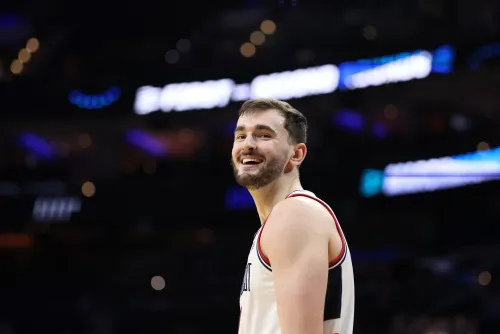 ابتسامة أليكس كارابان، لاعب كرة السلة في جامعة يوكوكون، خلال مباراة، مع التركيز على تطوره كلاعب وأهمية استمراره في الكلية.