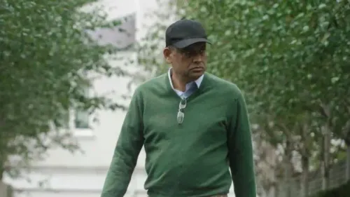 سيف الزمان شودري، وزير الأراضي البنغلاديشي السابق، يتجول في حي بلندن، وسط أشجار، مع نظارات وقبعة.