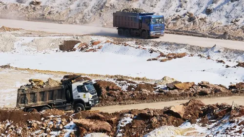 شاحنات نقل كبيرة تعمل في موقع تعدين، محملة بالصخور والمعادن في منطقة ثلجية، تعكس جهود أوكرانيا لتعزيز مواردها الطبيعية.