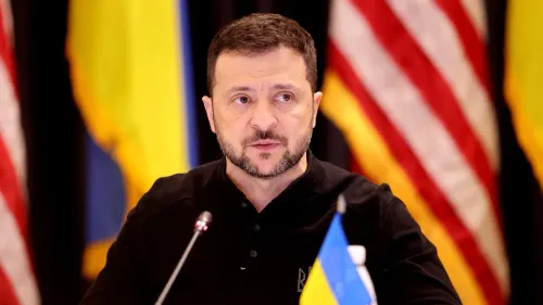 الرئيس الأوكراني فولوديمير زيلينسكي يتحدث خلال مؤتمر صحفي، مع العلم الأوكراني وخلفية الأعلام الأمريكية، مستعرضًا مصالح أوكرانيا في زمن الحرب.