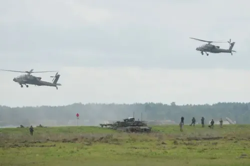 تظهر الصورة مروحيتين عسكريتين تحلقان فوق مجموعة من الجنود والدبابات في منطقة تدريب، مما يعكس التعاون العسكري بين أوكرانيا وبولندا.