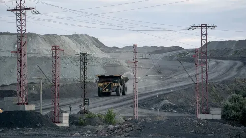 مشهد لموقع تعدين في أوكرانيا، حيث تسير شاحنة كبيرة على طريق محاط بتضاريس جبلية، مما يبرز أهمية الموارد المعدنية في سياق الدعم العسكري الأمريكي.