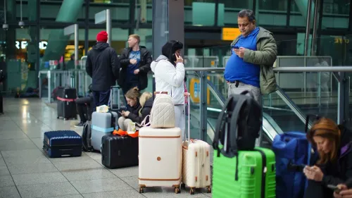 تظهر الصورة مسافرين عالقين في مطار هيثرو، محاطين بأمتعتهم، حيث يعبرون عن الإحباط بسبب إغلاق المطار الذي أثر على رحلاتهم.