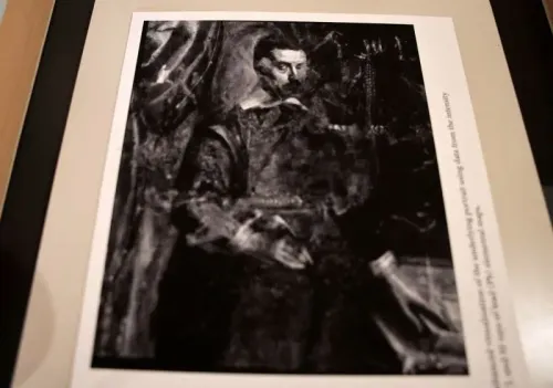 رجل مجهول بشارب رفيع وريشة في يده، يقف بجانب كومة من الأوراق، يظهر تحت لوحة تيتيان المخبأة في ليماسول.