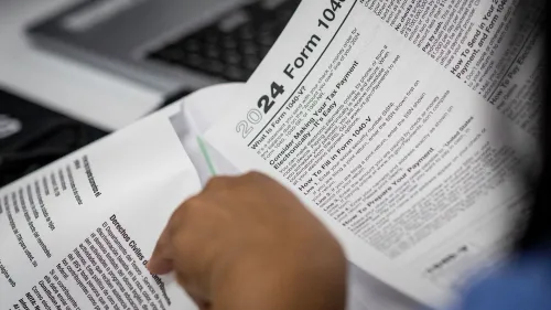 استمارة ضريبة الدخل لعام 2024، تُظهر يدًا تحمل الوثيقة مع نصوص تتعلق بالضرائب وحقوق المواطنين، تعكس أهمية المهاجرين في النظام المالي.