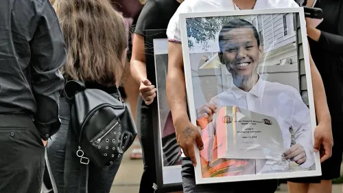 تجمع حشد من الأشخاص في يوتيكا، حيث يحمل أحدهم صورة لشاب مبتسم يحمل شهادة تخرج، في ذكرى مأساة نياه مواي.