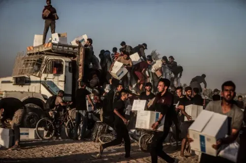 مشهد لمجموعة من الفلسطينيين يتجمعون حول شاحنة توصيل المساعدات في غزة، حيث يحملون صناديق الطعام وسط ظروف صعبة.