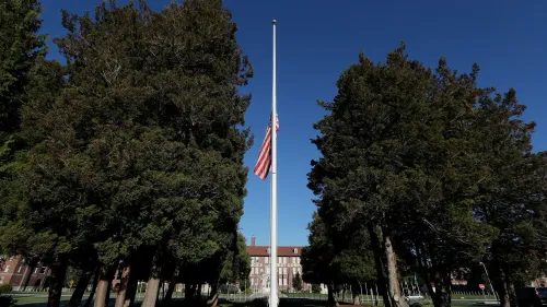 علم أمريكي مرفوع على سارية في قاعدة عسكرية، محاط بأشجار، في سياق اعتقالات جنديين بتهمة بيع أسرار عسكرية للصين.