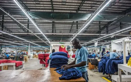 عمال في مصنع في جمهورية الدومينيكان يقومون بترتيب الملابس، مما يعكس النمو في قطاع التصنيع بالبلاد وجذب الاستثمارات الأجنبية.
