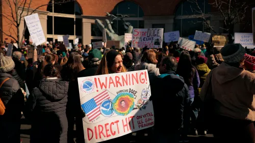 تجمع حاشد أمام مبنى حكومي، حيث يحمل المتظاهرون لافتات تحذر من تأثير DOGE على البرامج الحكومية الحيوية.