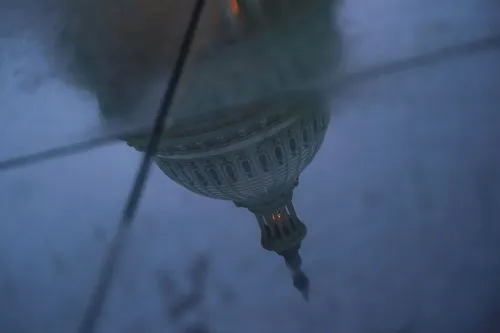 انعكاس لمبنى الكابيتول الأمريكي في بركة ماء، يعكس حالة عدم اليقين السياسي بعد الإغلاق الحكومي.