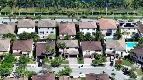 منازل في حي سكني أمريكي، مع مناظر طبيعية، تعكس تراجع مبيعات المنازل وارتفاع الأسعار في عام 2024.