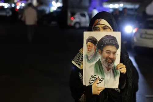 امرأة ترتدي حجابًا وتحمل صورة لرجلين، أحدهما مبتسم والآخر يبدو جادًا، في سياق مظاهرة أو تجمع في الشارع.