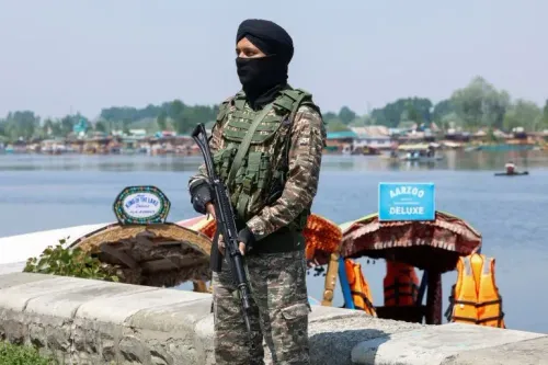 جندي مسلح يقف في حالة تأهب على ضفاف بحيرة في كشمير، مع قوارب سياحية في الخلفية، في ظل توترات أمنية بعد هجوم بهالغام.