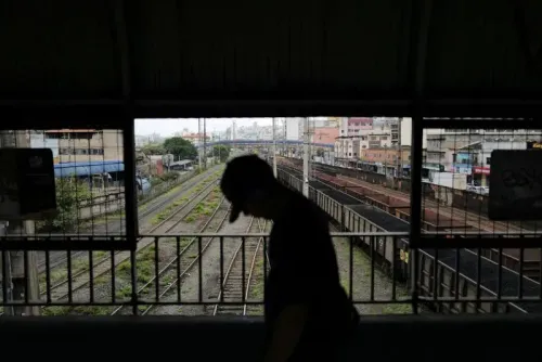 مشهد لراكب يسير في محطة قطار، مع خطوط السكك الحديدية والمباني في الخلفية، يعكس حركة النقل في البرازيل وسط التوترات التجارية.