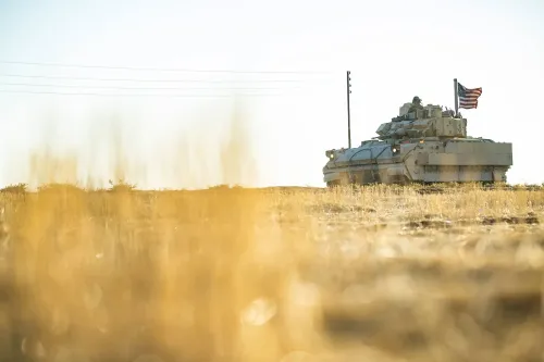 دبابة أمريكية تحمل العلم الوطني، متواجدة في منطقة صحراوية، تعكس استمرار العمليات العسكرية ضد داعش في سوريا.