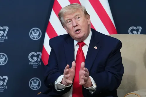 اجتماع قادة مجموعة السبع (G7) في فرنسا، حيث يتحدث ترامب بزيه الرسمي، مع العلميات الأمريكية في خلفية الصورة.