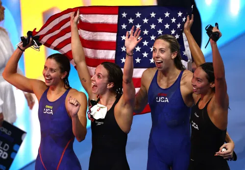 فريق السباحة الأمريكي يحتفل بفوزهم بالميدالية الذهبية في سباق التتابع 4×100 متر متنوع، مع رفع العلم الأمريكي، في بطولة العالم للألعاب المائية.