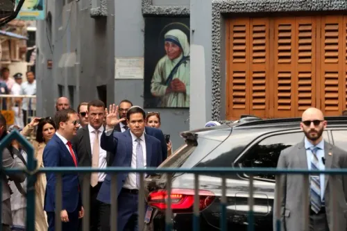 وزير الخارجية الأمريكي ماركو روبيو يلوح بيده أثناء مغادرته ضريح الأم تيريزا في كولكاتا، مع وجود صورة للأم تيريزا خلفه.