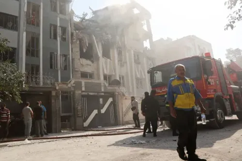 دمار هائل في مبنى سكني نتيجة القصف، مع وجود رجال إنقاذ وآليات إطفاء في الموقع، مما يعكس تصاعد التوترات بين إيران وإسرائيل.
