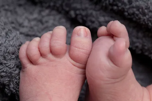 أقدام طفلين حديثي الولادة، تظهر تفاصيل الأصابع والجلد، تعكس موضوع وفيات الأجنة وتحسينات الرعاية الصحية.