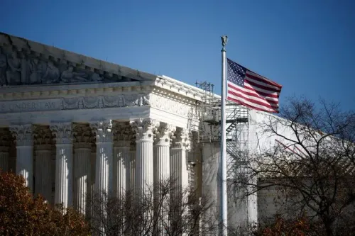 واجهة المحكمة العليا الأمريكية مع أعمدة بارزة وعلم الولايات المتحدة يرفرف في الهواء، تعكس الجدل حول إعادة رسم الدوائر الانتخابية.
